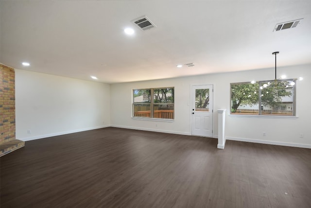 unfurnished living room featuring a notable chandelier and dark hardwood / wood-style flooring