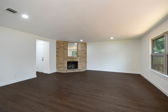 unfurnished living room with a brick fireplace and dark wood-type flooring