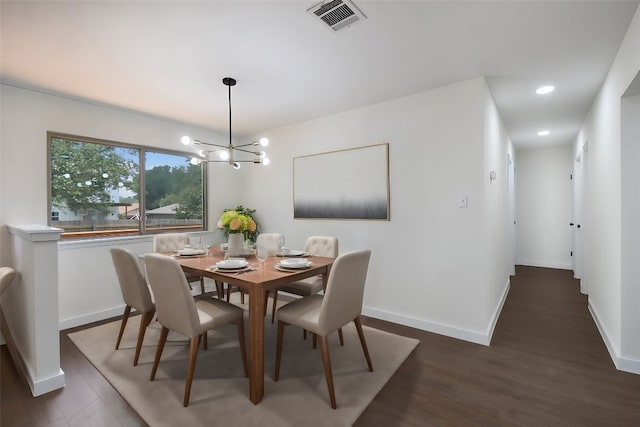 dining room with dark wood-type flooring and an inviting chandelier