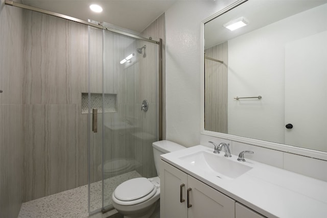 bathroom featuring vanity, a shower with shower door, and toilet