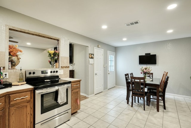 kitchen featuring stainless steel electric range oven, light tile flooring, and tasteful backsplash