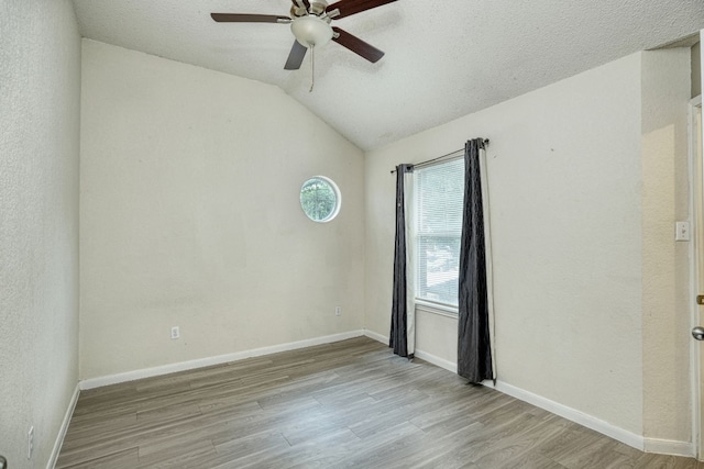 unfurnished room featuring a textured ceiling, lofted ceiling, light wood-type flooring, and ceiling fan