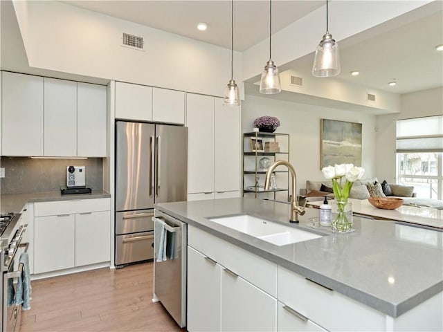 kitchen with decorative light fixtures, stainless steel appliances, decorative backsplash, white cabinets, and sink