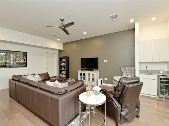 living room featuring ceiling fan, light wood-type flooring, and wine cooler