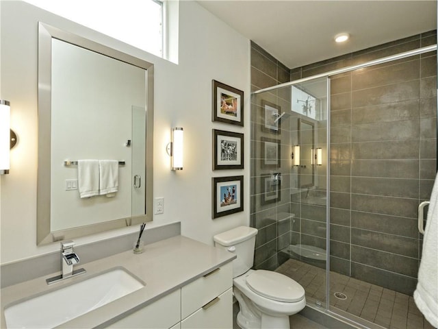 bathroom with toilet, a shower with shower door, and vanity