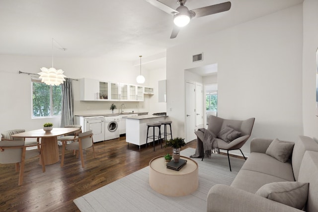 living room with dark wood-type flooring, lofted ceiling, washer / clothes dryer, sink, and ceiling fan