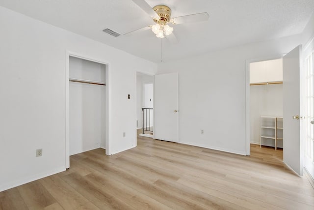 unfurnished bedroom featuring multiple closets, ceiling fan, and light hardwood / wood-style floors