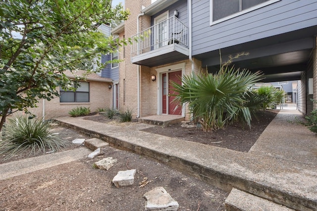 view of exterior entry with a balcony