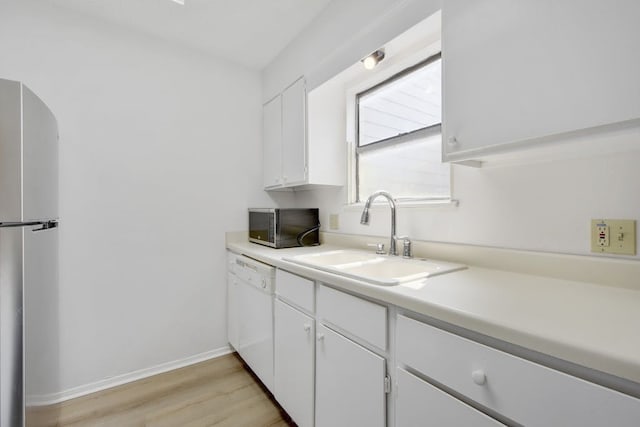 kitchen featuring stainless steel appliances, sink, white cabinetry, and light hardwood / wood-style floors