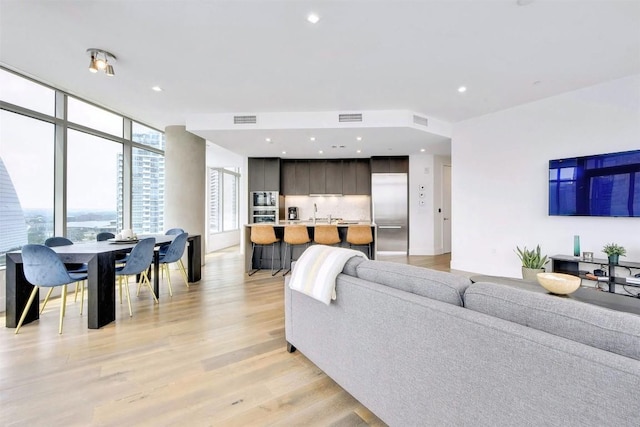 living room with a wall of windows and light hardwood / wood-style flooring