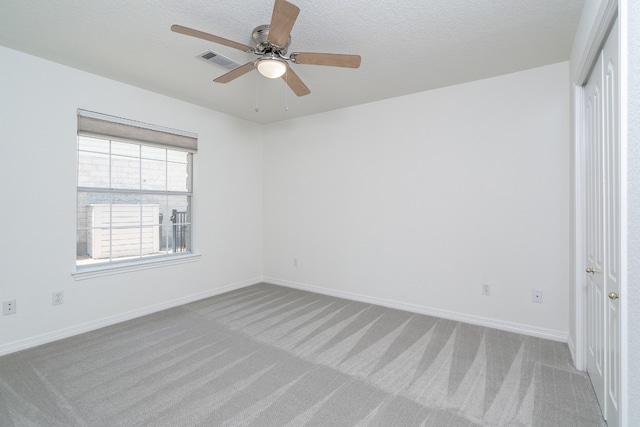 carpeted spare room featuring ceiling fan and a textured ceiling