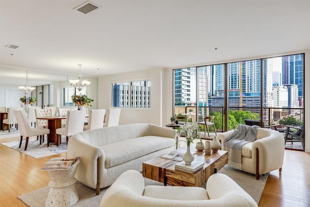 living room with a chandelier, visible vents, light wood-style flooring, and floor to ceiling windows