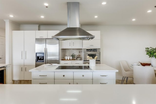 kitchen featuring light countertops, ornamental molding, decorative backsplash, island exhaust hood, and stainless steel appliances