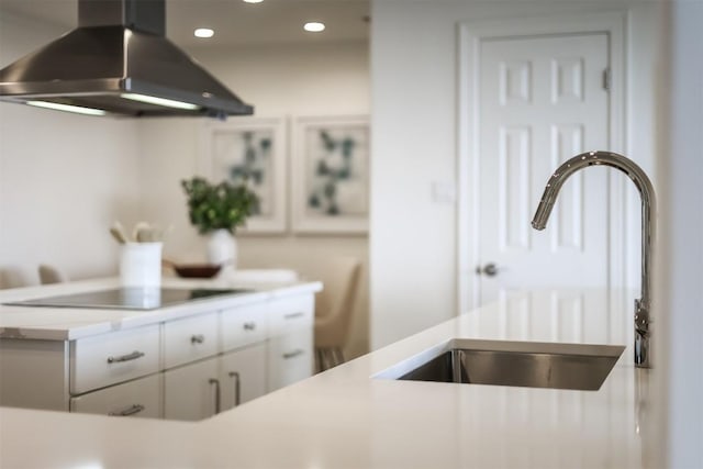 kitchen featuring ventilation hood, a sink, light countertops, white cabinetry, and black electric stovetop