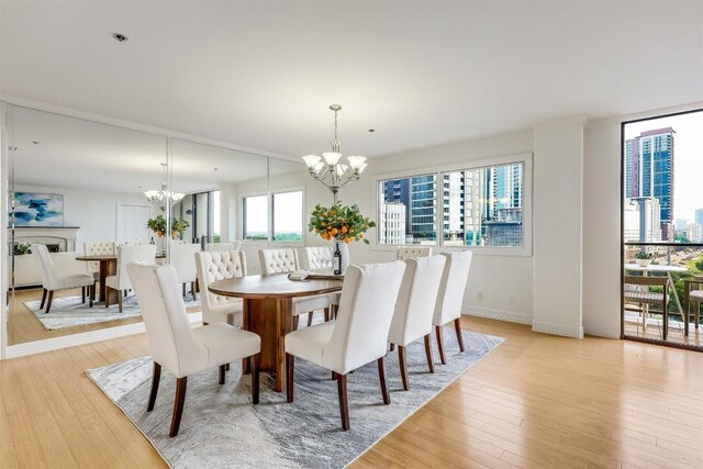 dining space with light wood-type flooring, baseboards, and a chandelier