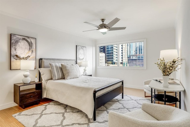 bedroom featuring baseboards, wood finished floors, and a ceiling fan