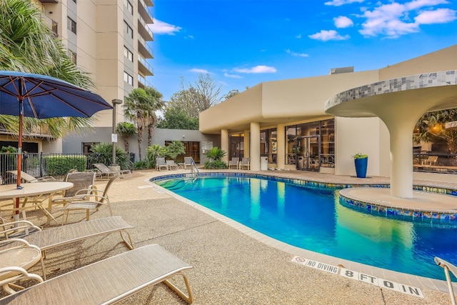 community pool with a patio area and fence