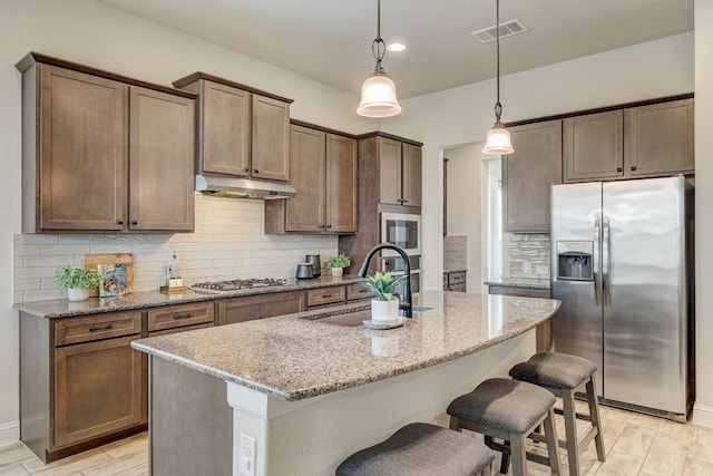 kitchen with stainless steel appliances, light stone counters, light hardwood / wood-style floors, and sink