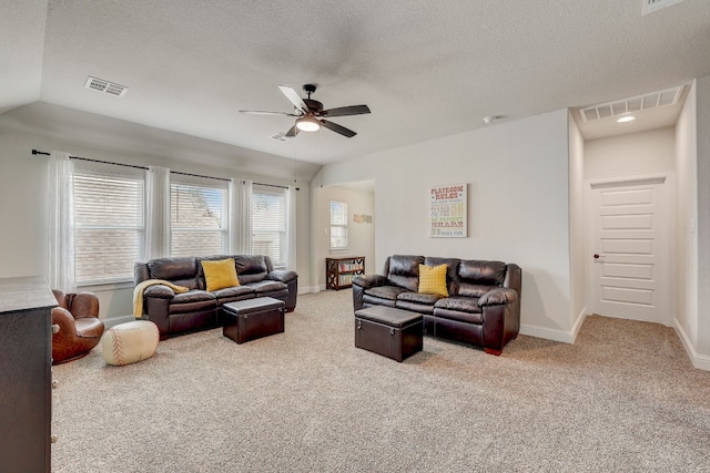 living room featuring lofted ceiling, ceiling fan, light colored carpet, and a textured ceiling