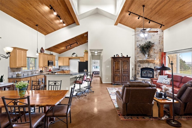 dining space with high vaulted ceiling, ceiling fan, wooden ceiling, and a stone fireplace