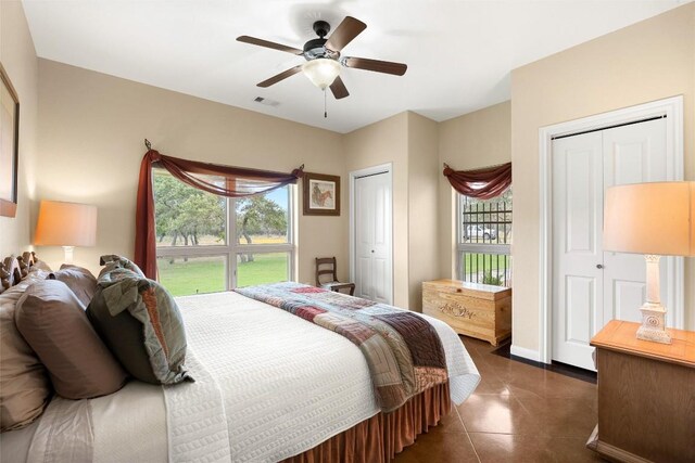 bedroom with multiple windows, ceiling fan, and multiple closets