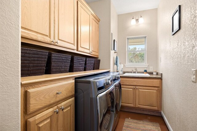clothes washing area with washer and dryer, cabinets, and sink
