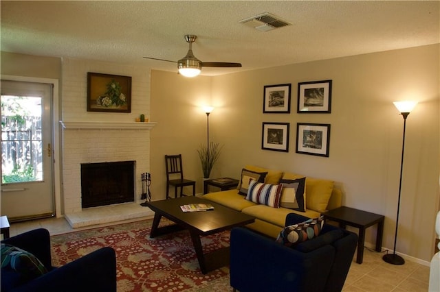 tiled living room featuring a textured ceiling, ceiling fan, and a fireplace