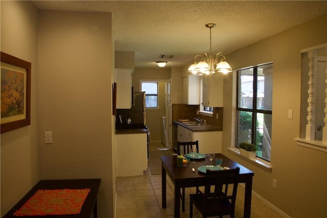 dining room featuring a chandelier, a textured ceiling, and light tile floors