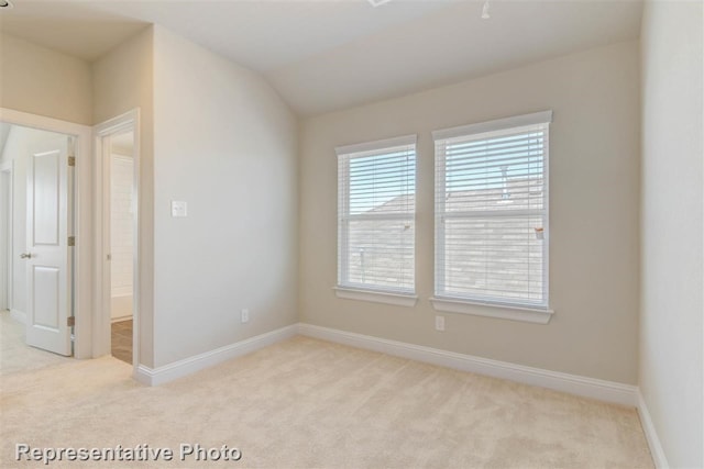 empty room with lofted ceiling and light carpet