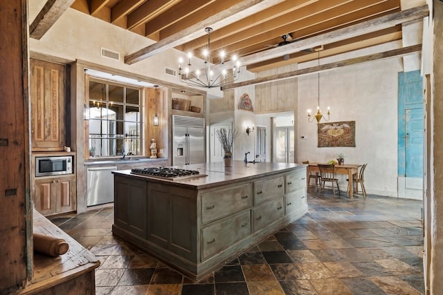 kitchen with a center island, hanging light fixtures, built in appliances, and dark tile floors