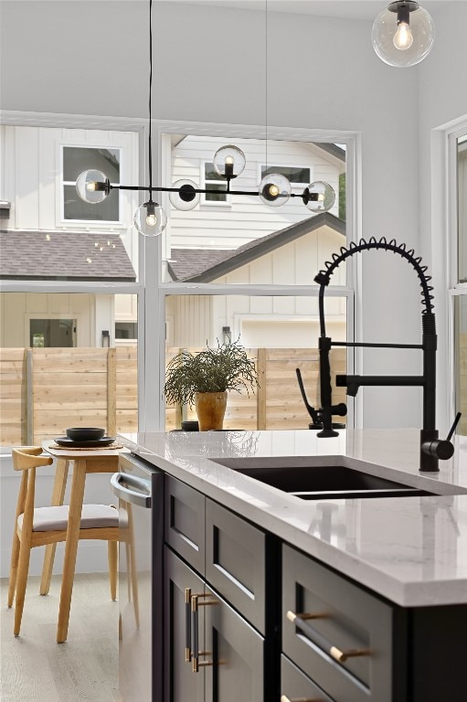 bar with light stone counters, sink, and hanging light fixtures