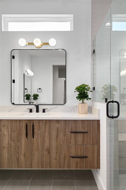 bathroom featuring tile patterned floors, vanity, a shower with shower door, and plenty of natural light