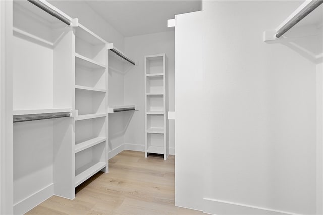 walk in closet with light hardwood / wood-style flooring