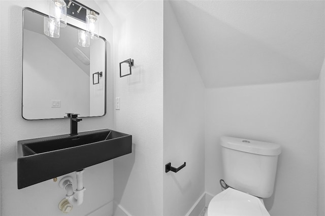 bathroom featuring sink, toilet, and vaulted ceiling