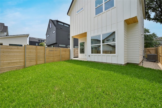 back of property with central AC unit and a yard