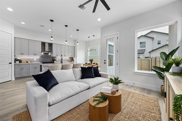 living room with ceiling fan, sink, and light hardwood / wood-style floors