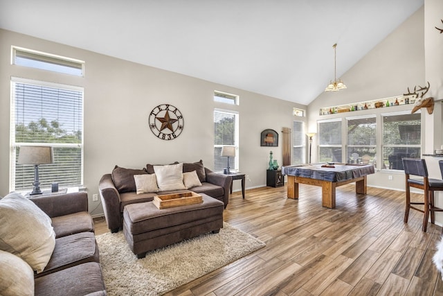 living room with high vaulted ceiling, plenty of natural light, and wood finished floors