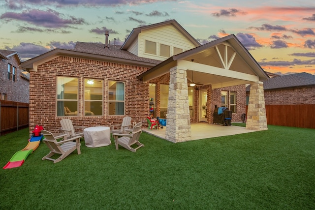 back house at dusk with a lawn and a patio area