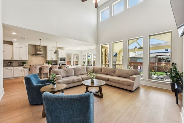 living room with a towering ceiling, plenty of natural light, and light hardwood / wood-style flooring