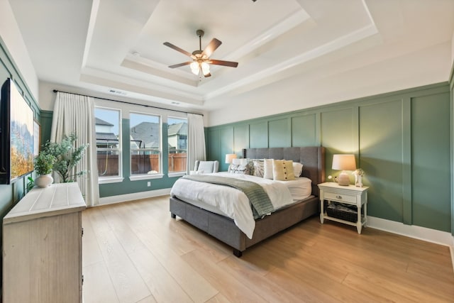 bedroom featuring a tray ceiling, light wood-type flooring, and ceiling fan