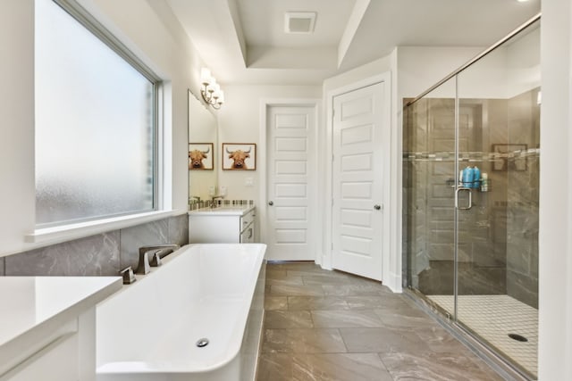 bathroom with vanity, a raised ceiling, and shower with separate bathtub