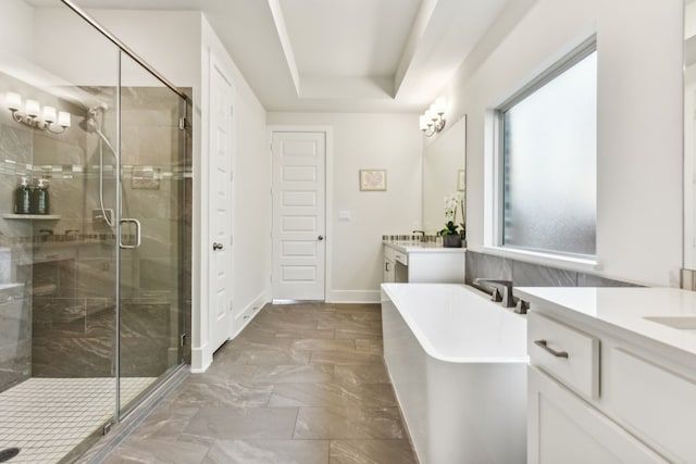 bathroom featuring a raised ceiling, separate shower and tub, and vanity