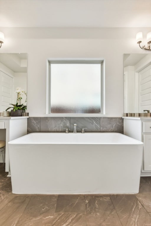 bathroom featuring a healthy amount of sunlight, vanity, and a bath