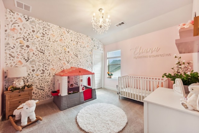 bedroom with a crib, carpet flooring, and a chandelier