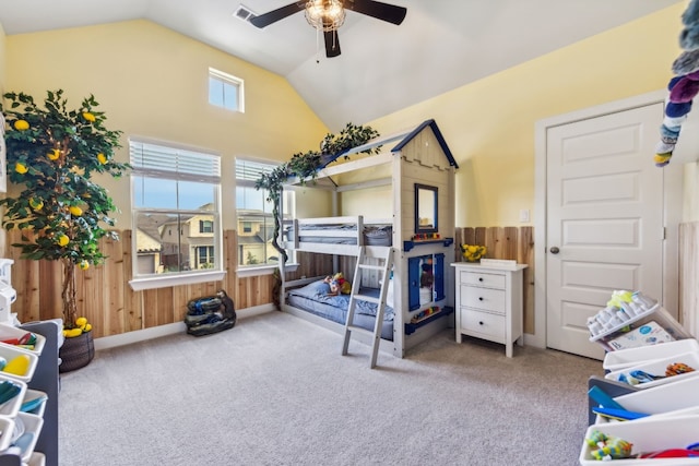 bedroom featuring ceiling fan, vaulted ceiling, wooden walls, and light carpet