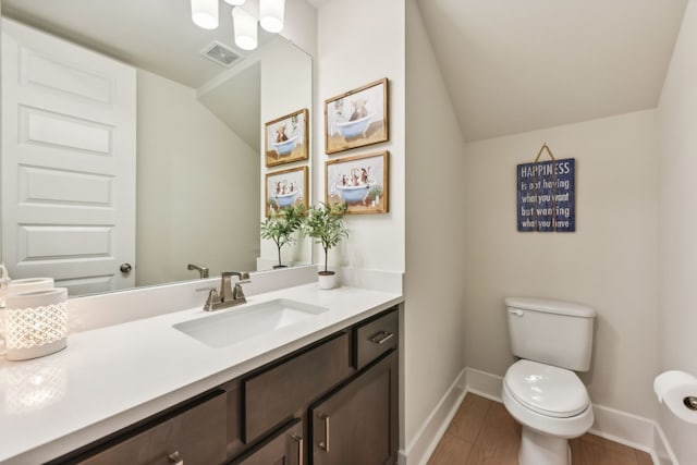 bathroom featuring lofted ceiling, wood-type flooring, vanity, and toilet