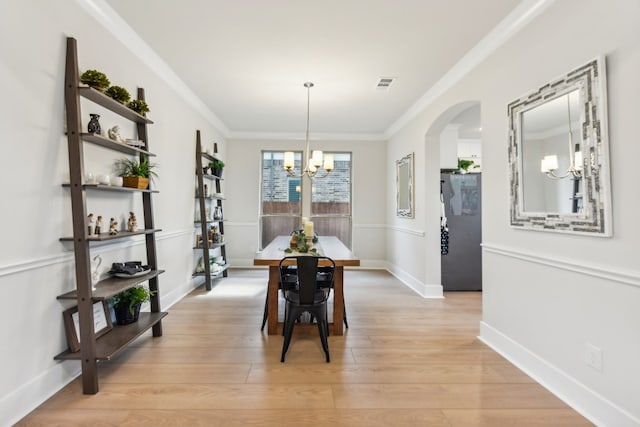 dining area featuring a notable chandelier, light wood-type flooring, and crown molding