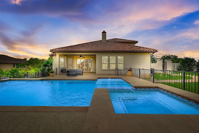 pool at dusk with a patio and ceiling fan