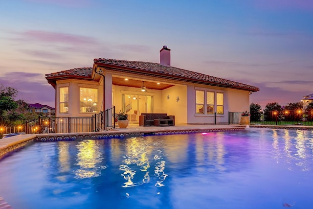 pool at dusk featuring a patio and ceiling fan