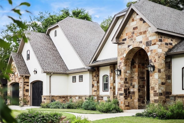 view of front of house with stone siding, roof with shingles, and stucco siding